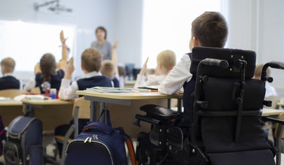 a child in a wheelchair sitting in a classroom